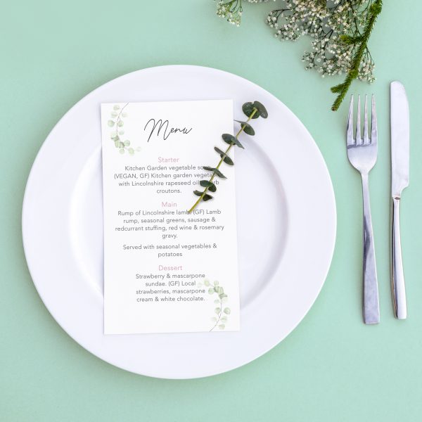 Dinner menu for a wedding or luxury evening meal. Table setting from above. Elegant empty plate, cutlery and flowers.